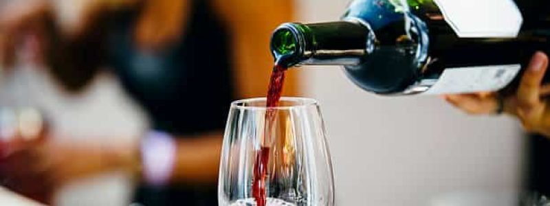 Man pouring red wine to wine glass.